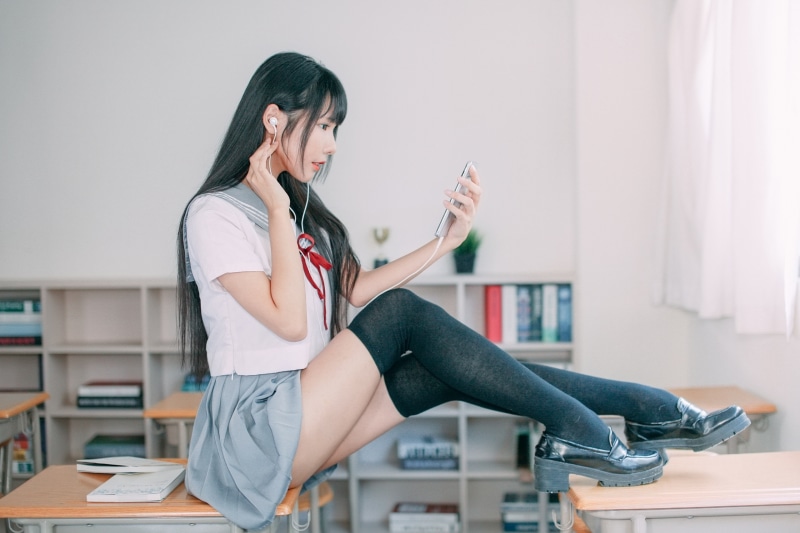Asian schoolgirl with smartphone and headphones