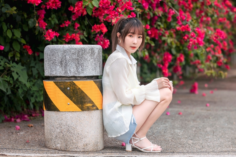 Asian woman posing by bougainvillea