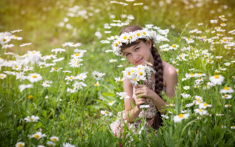 Girl with a wreath and bouquet of daisies in a field