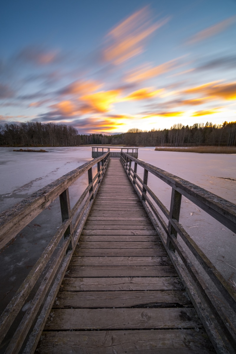 Wooden pier on a frozen lake at sunset
