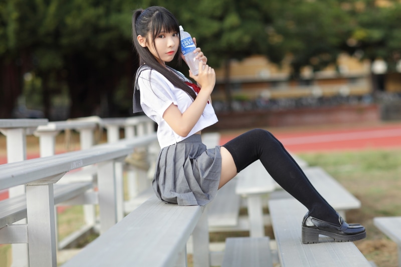 Asian girl in school uniform holding a bottle