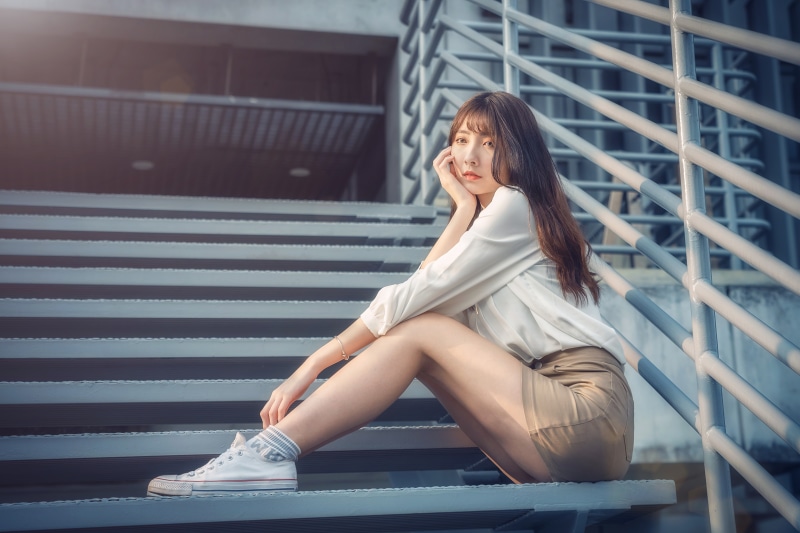 Asian woman with brown hair sitting on stairs