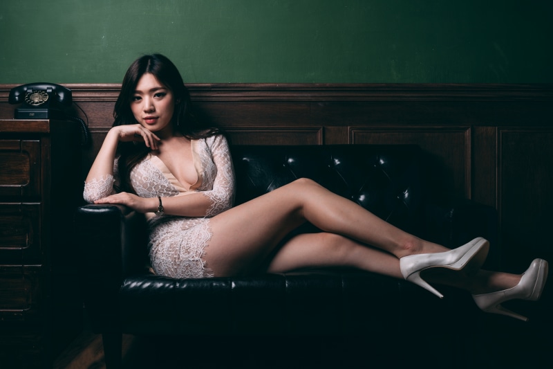 Asian woman in lace dress sitting on sofa