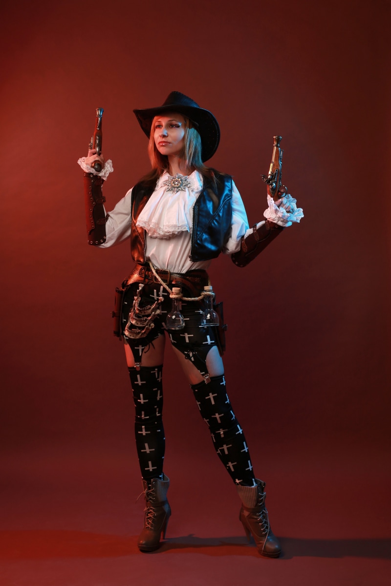 Woman in cowboy outfit holding pistols
