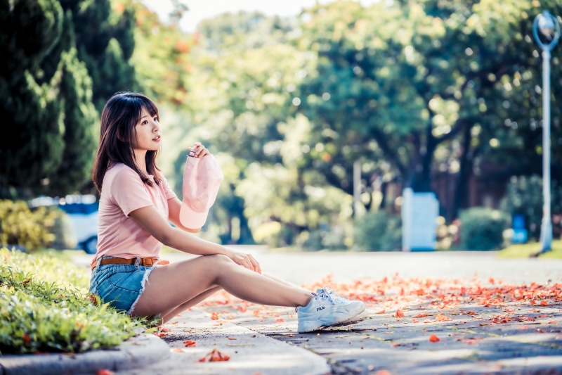 Asian girl in shorts and t-shirt holding baseball cap