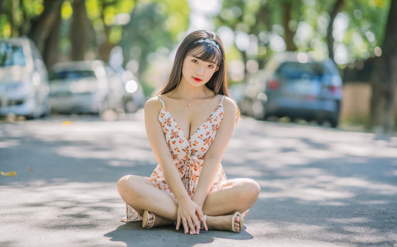 Asian woman in floral dress sitting on road