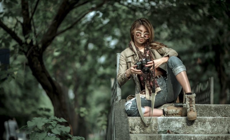 Asian woman with camera sitting on steps