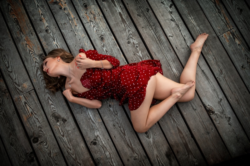 Diana lying on wooden planks in a red polka dot dress