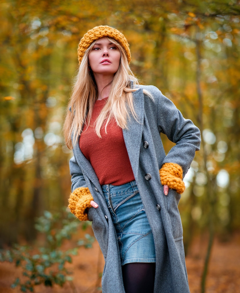 Woman wearing a coat and winter hat in autumn forest