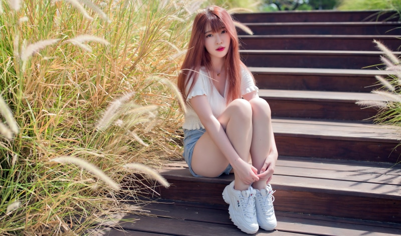 Asian girl with red hair sitting on wooden stairs