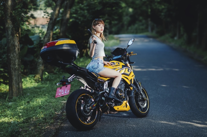 Asian woman with pistol sitting on Yamaha motorcycle