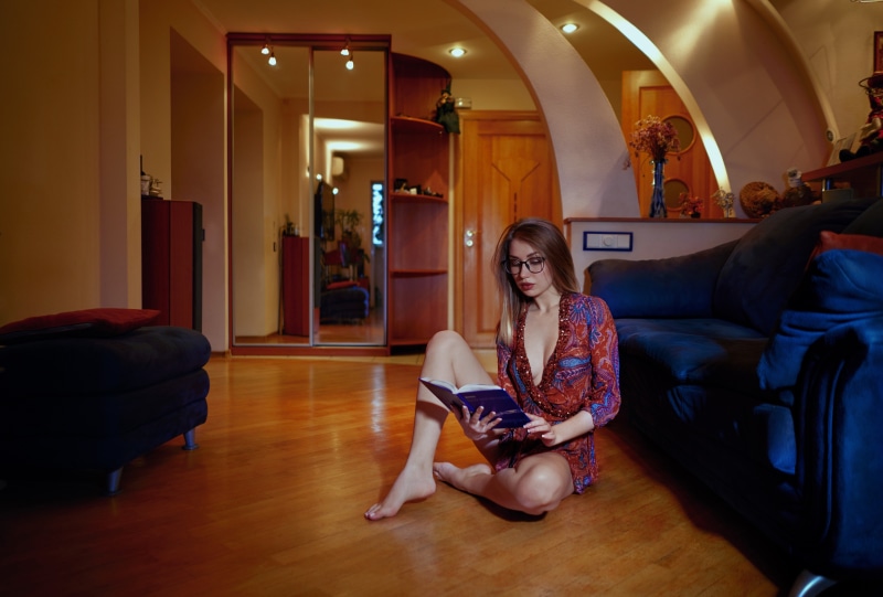 Woman in a patterned dress reading a book on the floor