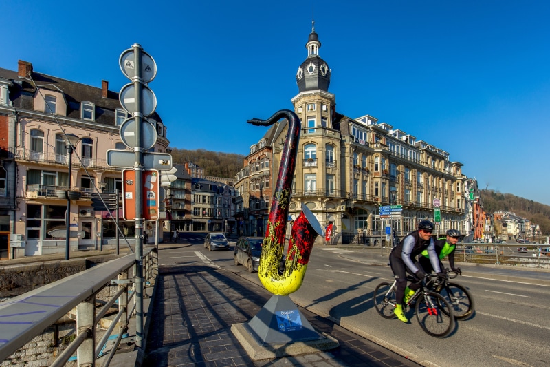 Saxophone sculpture and cyclists in Dinant, Belgium