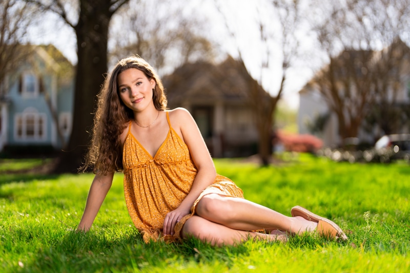 Girl in yellow dress sitting on grass