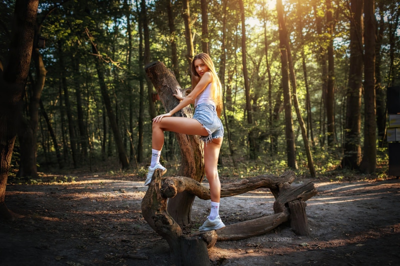 Woman posing on a log in a forest