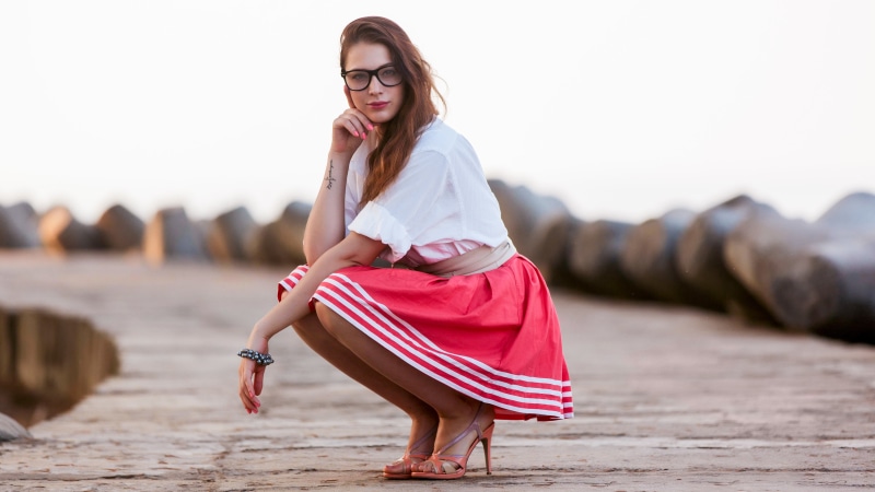 Woman with glasses and red skirt posing