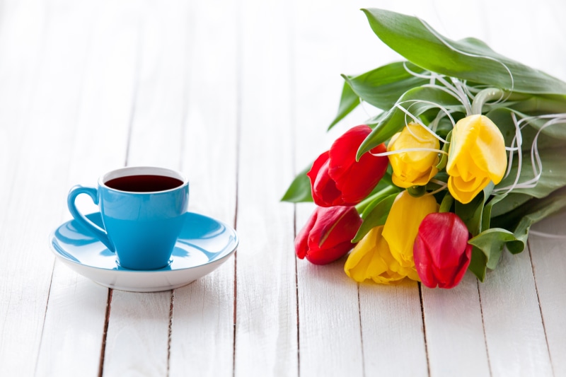 Blue coffee cup and red and yellow tulips