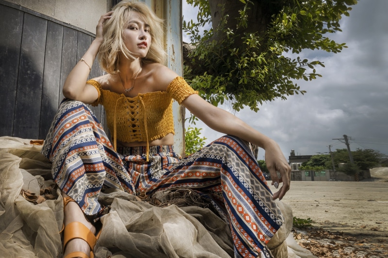 Blonde Asian woman sitting in patterned pants