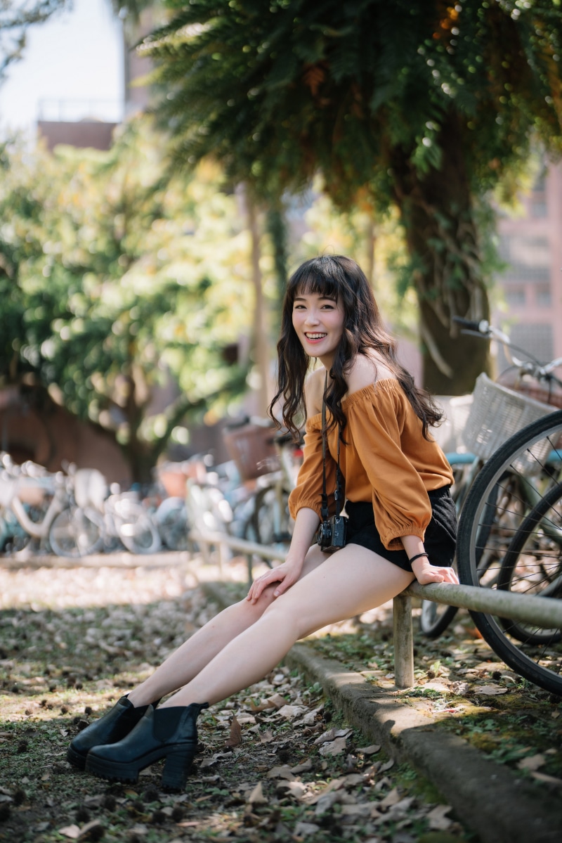 Asian woman with camera sitting outdoors