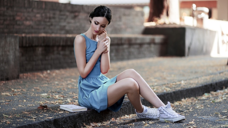 Brunette girl in blue dress sitting with book