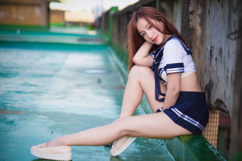 Asian woman in sailor uniform sitting outdoors