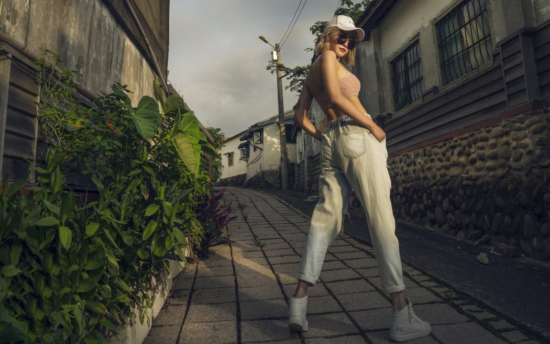Blonde girl in baseball cap and trousers on a street