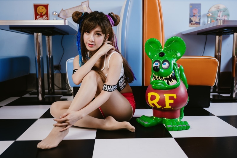 Asian woman posing in a diner with a rat figure