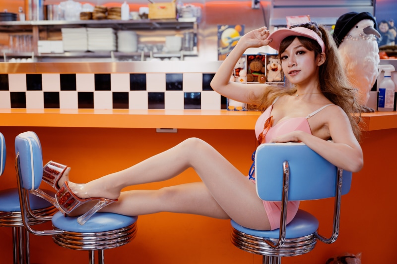 Asian woman in pink swimsuit sitting at diner counter