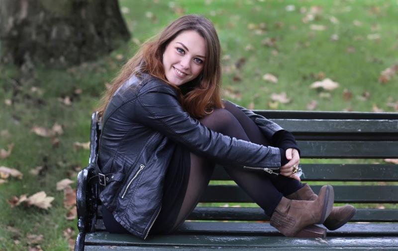 Woman in leather jacket sitting on a park bench