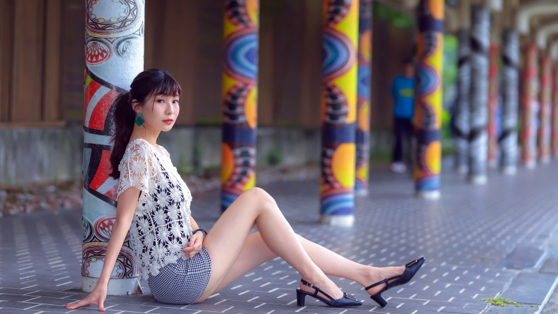 Asian woman sitting by colorful pillars