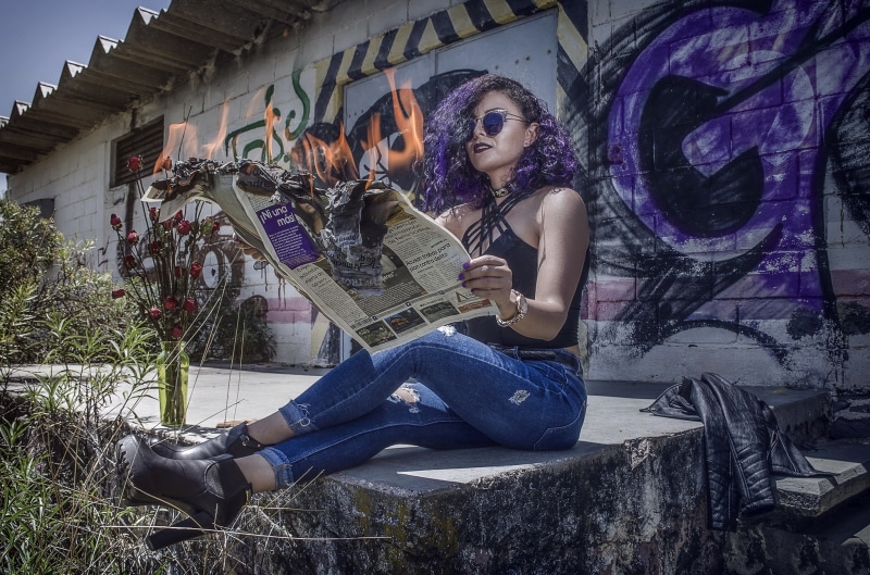 Woman burning newspaper while sitting outdoors