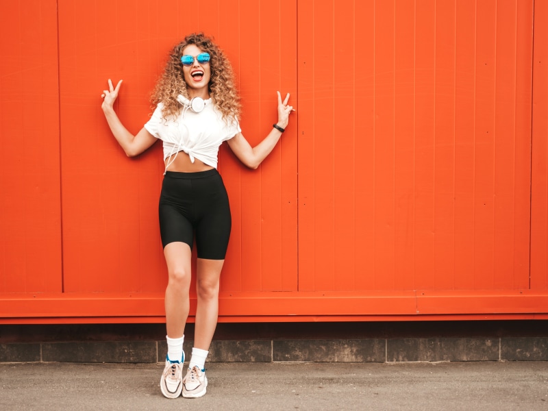 Blonde girl with curly hair wearing sunglasses and headphones