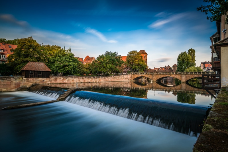River with a small waterfall and bridge in Nuremberg, Germany