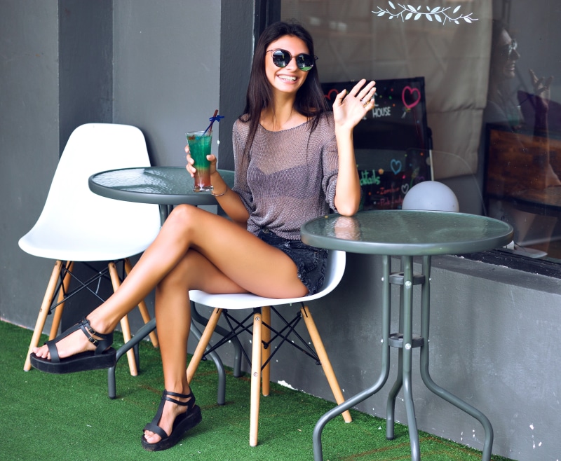 Brunette girl with sunglasses holding a drink at a cafe