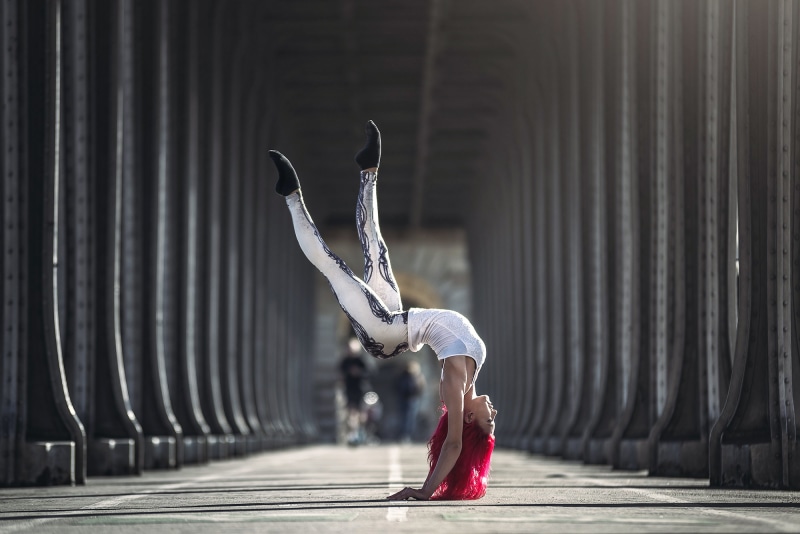 Woman performing gymnastics under a bridge