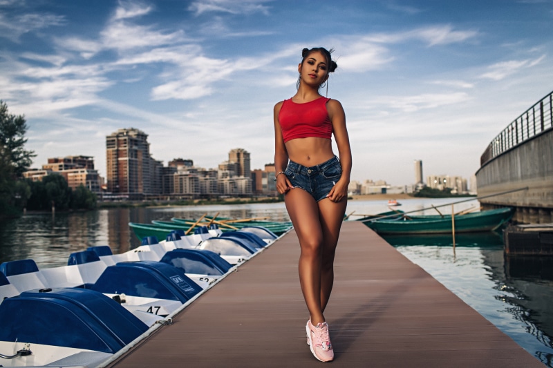 Brunette girl in shorts on a pier with boats
