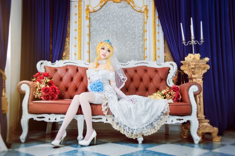 Bride in a white dress sitting on a sofa with flowers