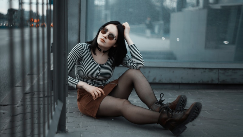Brunette girl with glasses sitting on the ground