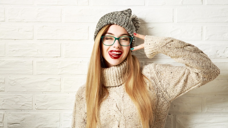 Girl in winter hat and sweater sticking out tongue