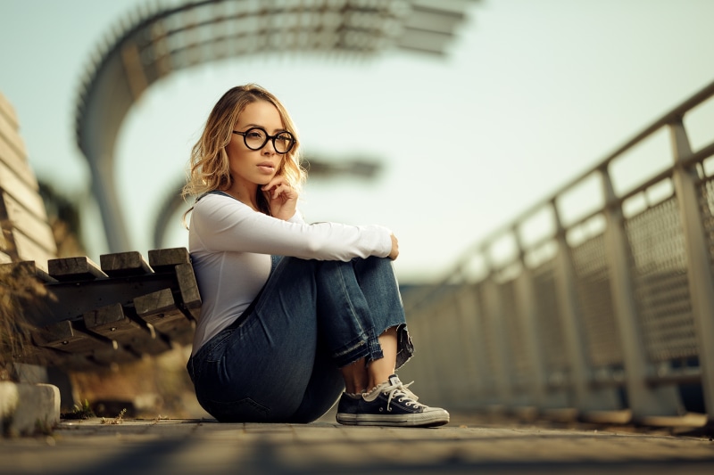 Blonde girl with glasses sitting on a bench