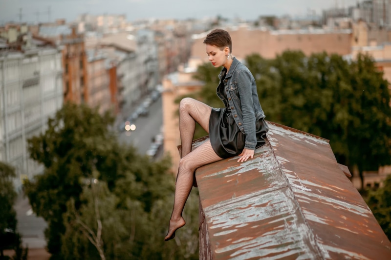 Daria Kazakova sitting on a rusty roof overlooking city