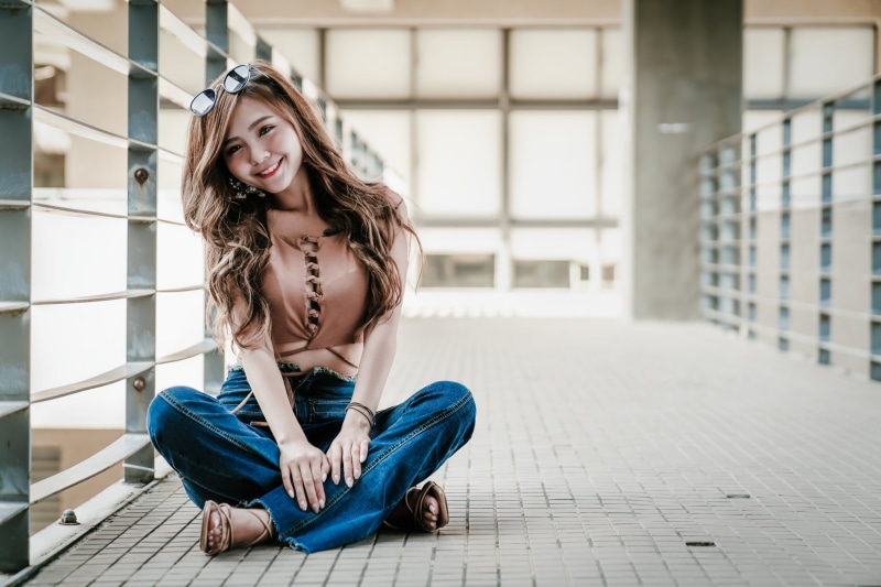 Asian woman with brown hair wearing jeans and sunglasses