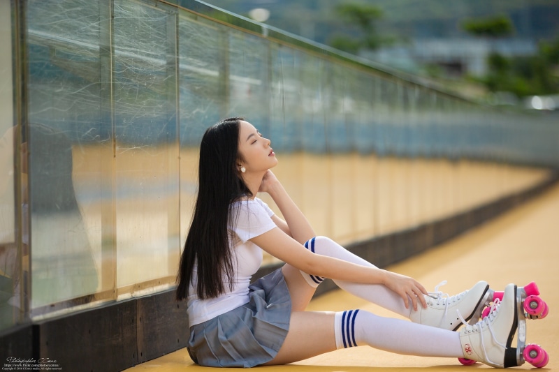 Asian girl in roller skates sitting on the ground