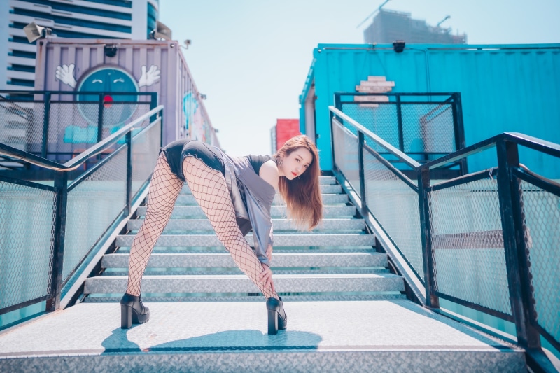 Asian woman in fishnet pantyhose and shorts posing on stairs