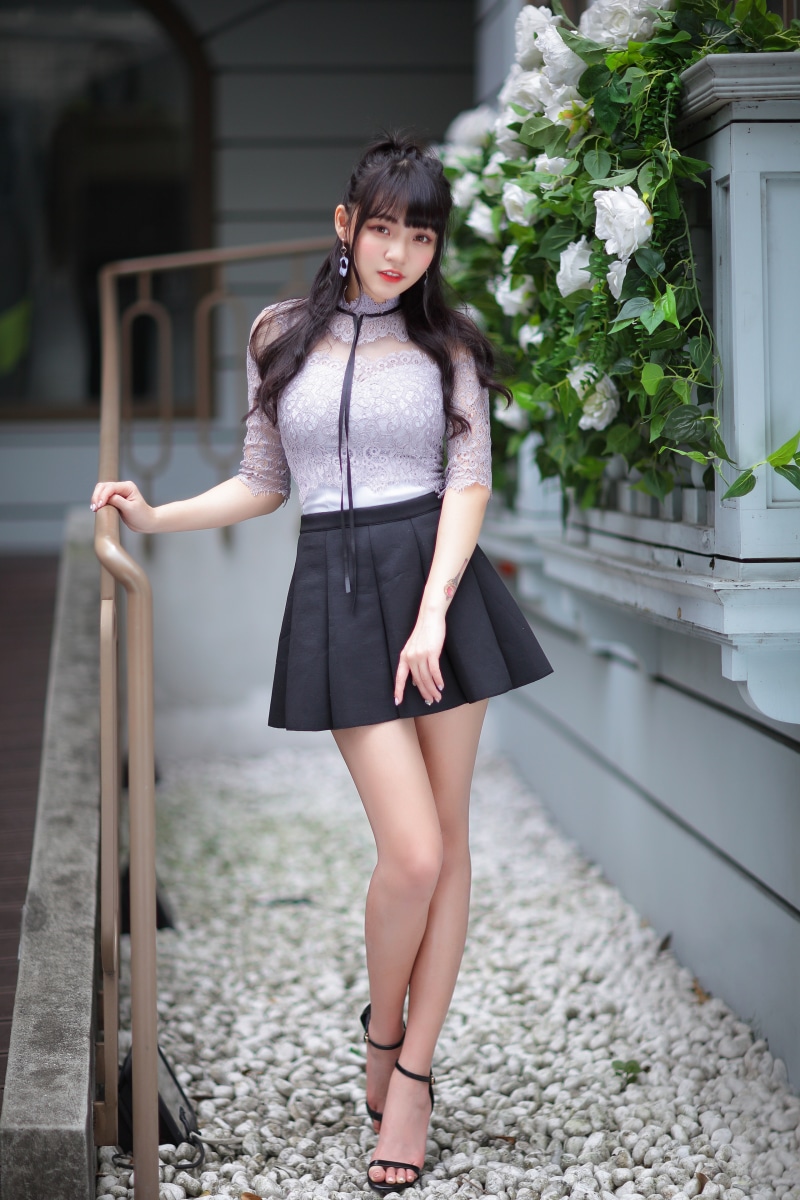 Asian girl in lace top and black skirt posing outdoors