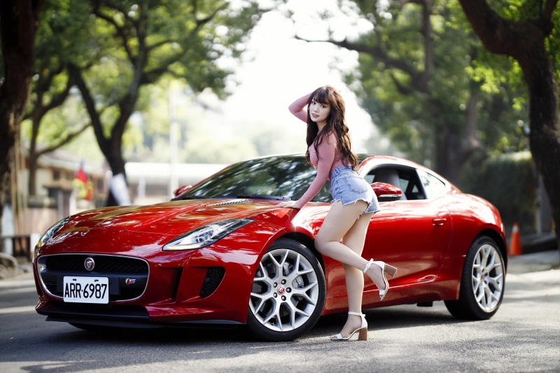 Brunette girl posing with a red Jaguar F-Type