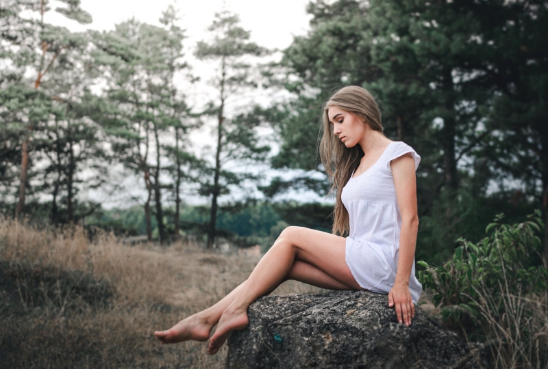 Woman in white dress sitting on a rock