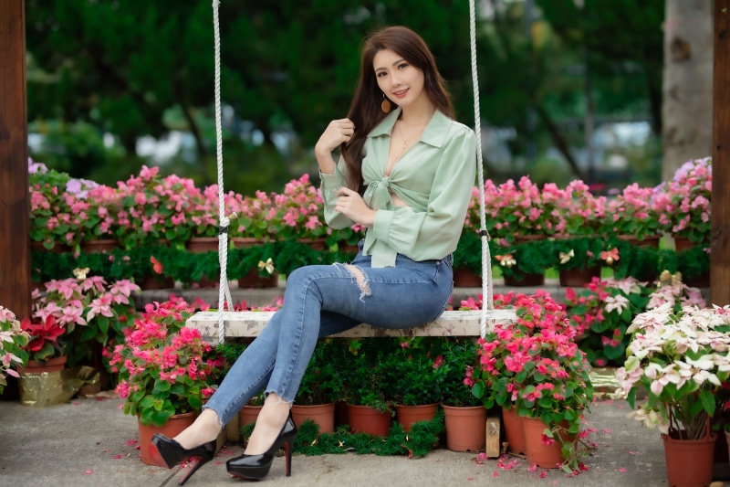 Asian woman sitting on a swing in a garden