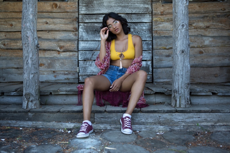 Woman in yellow top and denim shorts sitting on steps