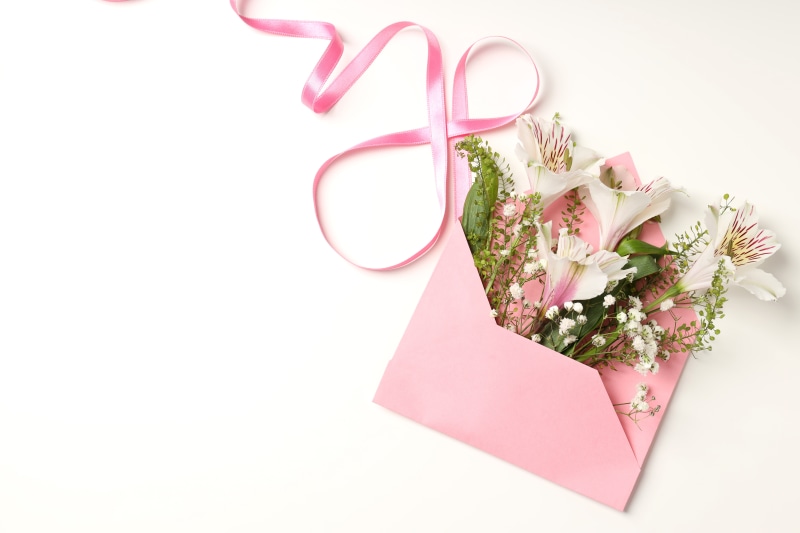 Bouquet of flowers in a pink envelope with a pink ribbon